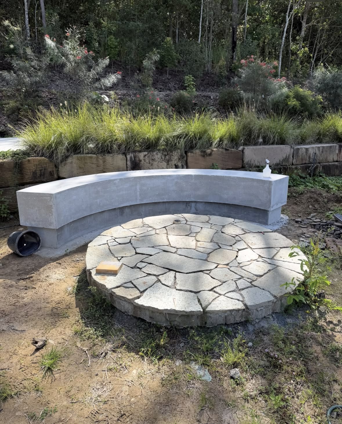 Curved built-in garden seat beside a circular stone-paved area