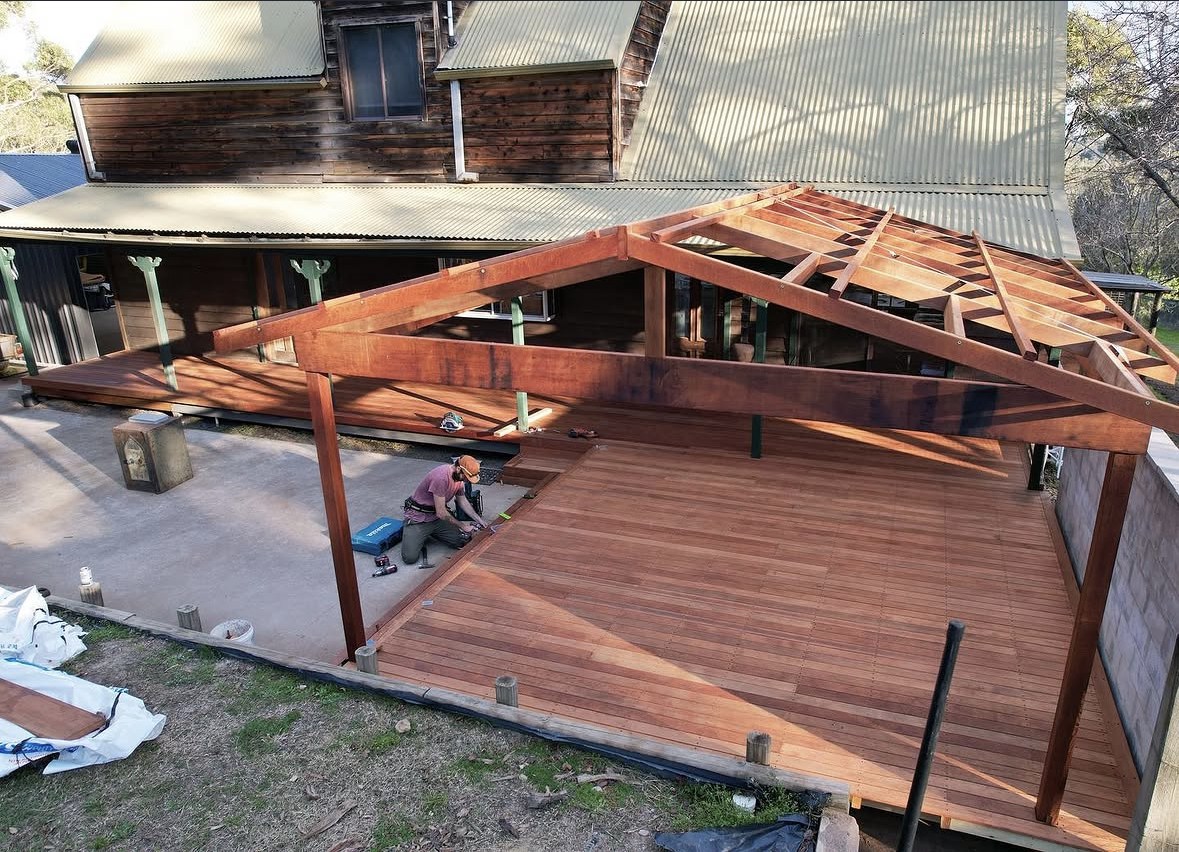 Timber deck and open pergola frame under construction beside a house