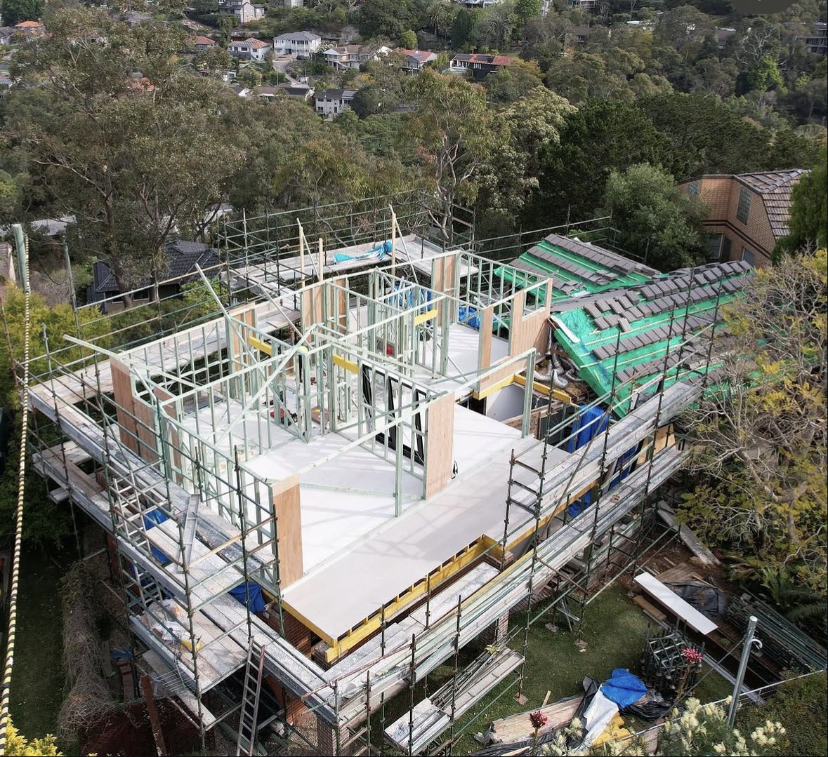 House under construction with upper-level framing and scaffolding around the building
